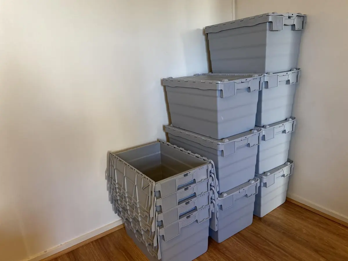 Stack of grey plastic moving crates with lids