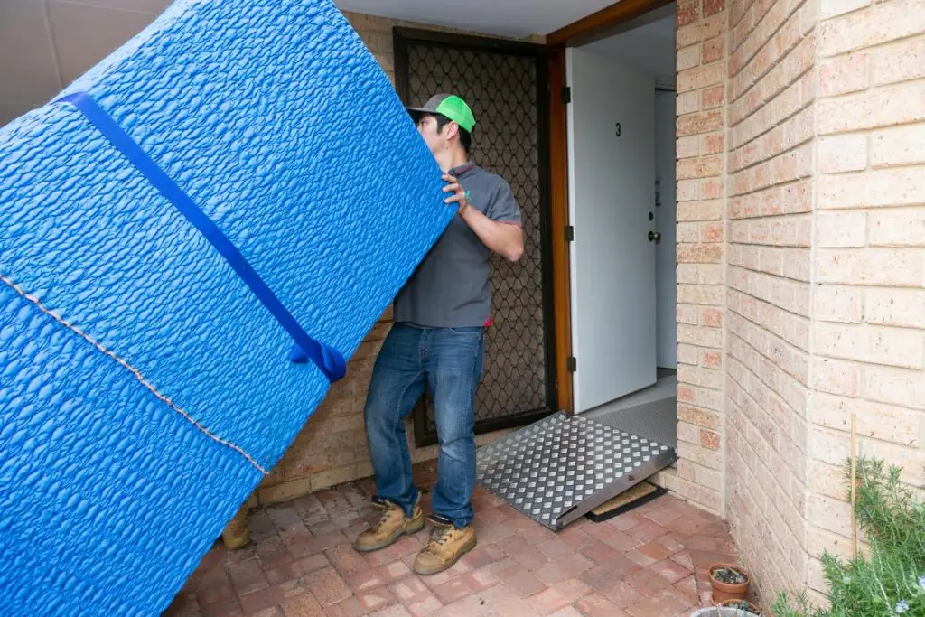 Mover carrying a blanket-wrapped item through a doorway